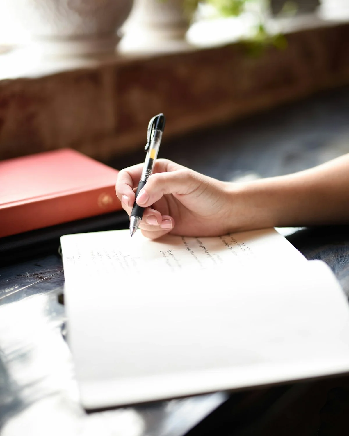 A hand writing a note in a notebook